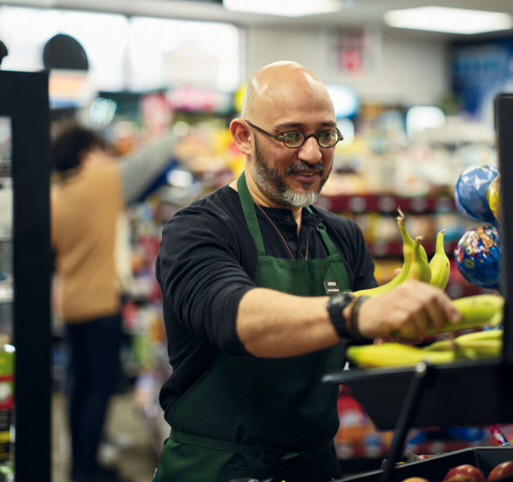 Grocery store employee stocking bananas in produce section